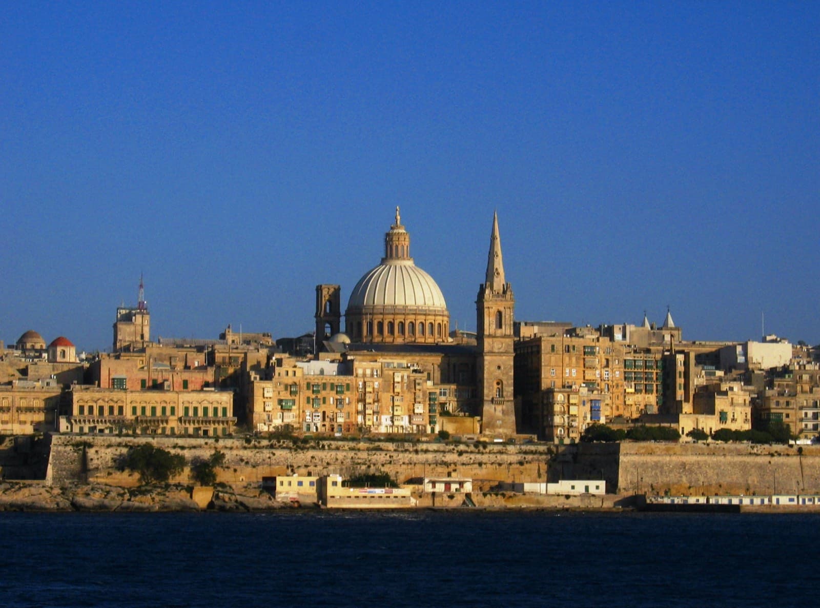 The Valletta skyline seen across the water, domed churches and sandstone buildings rising above the harbour
