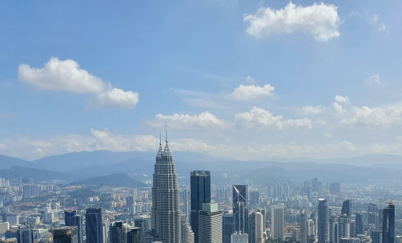 The Petronas Towers rising above the Kuala Lumpur skyline in daylight.