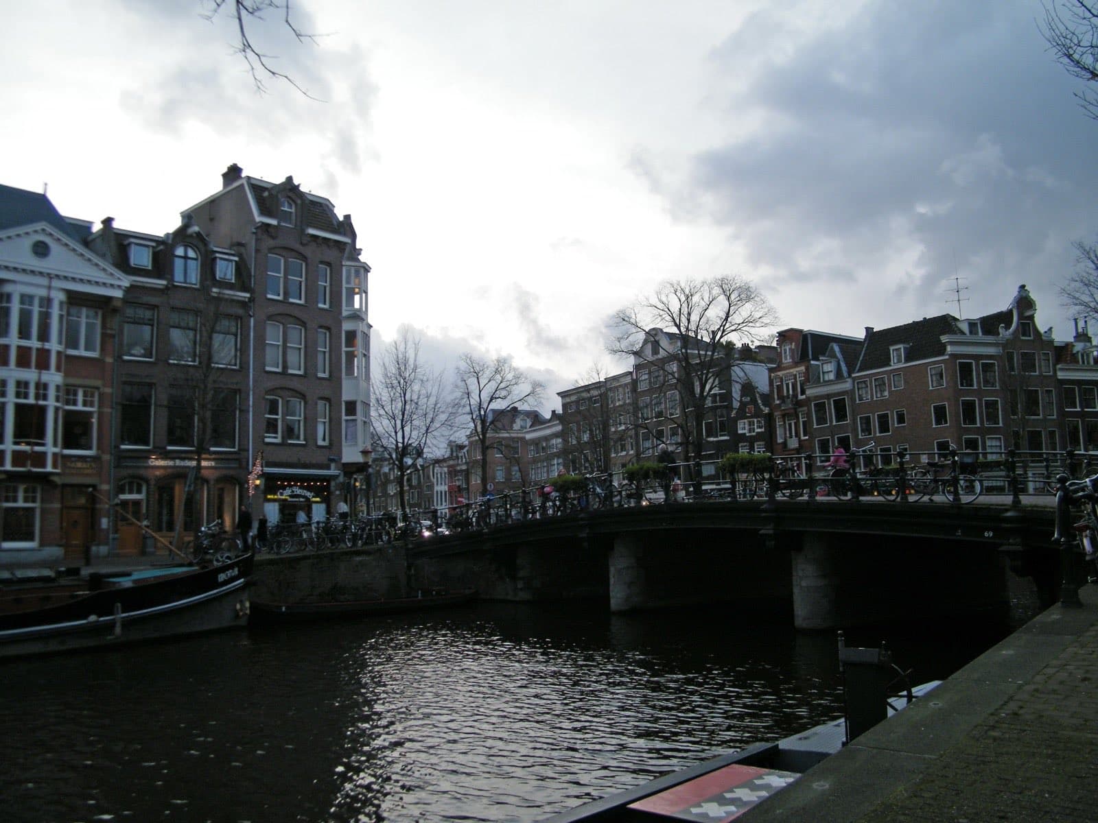A canal in Amsterdam lined with narrow gabled houses, a bridge crossing the water
