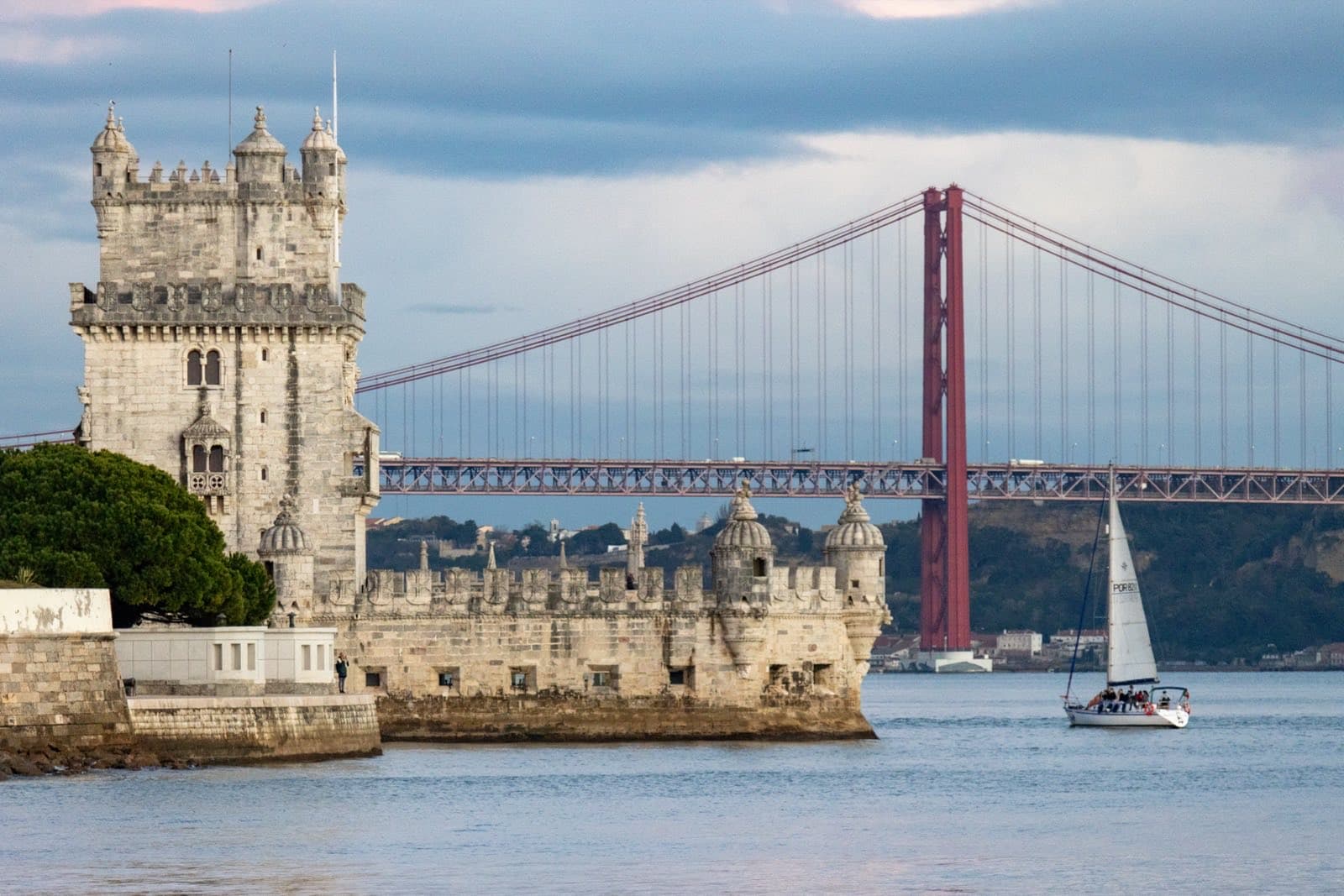 Belém Tower on the banks of the Tagus river in Lisbon, with the 25 de Abril suspension bridge visible in the background
