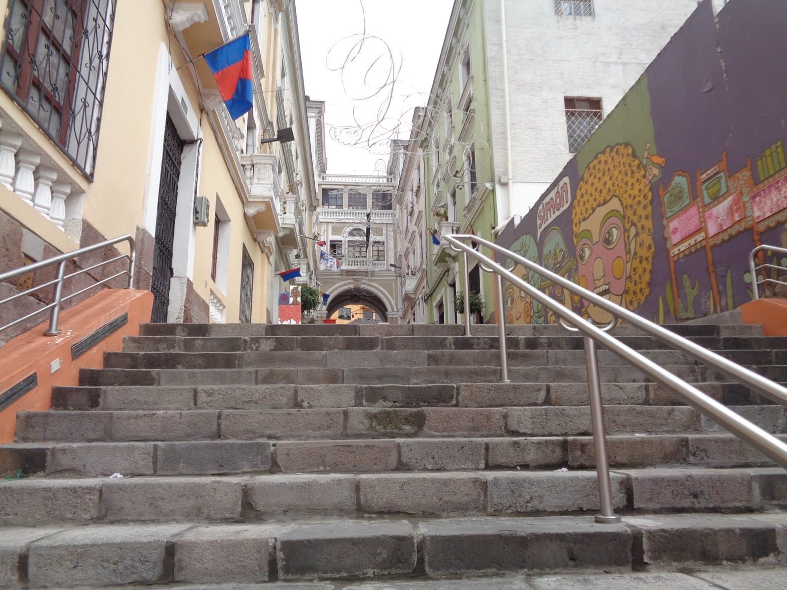 A colonial-era street in Quito's historic center, with the Andes visible in the distance
